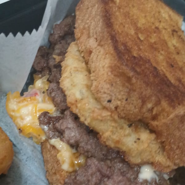 Close-up of a Southern Taste Cafe burger with melted cheese and a fried bun.