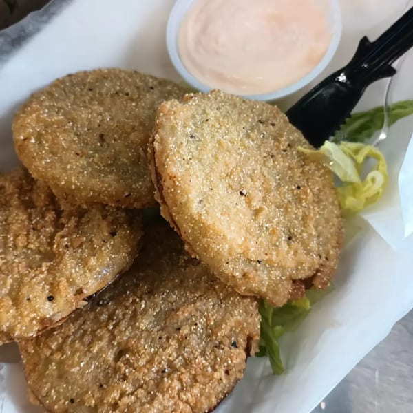 Crispy fried green tomatoes with a side of dipping sauce and lettuce from Southern Taste Cafe.