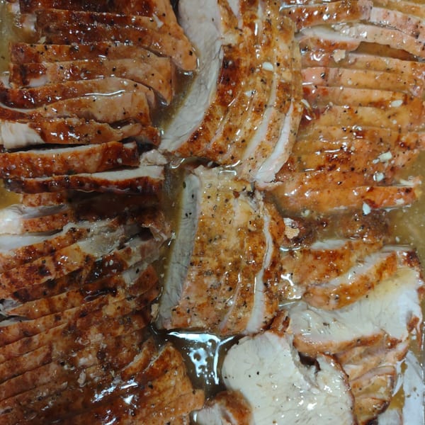 Close-up of sliced, seasoned Southern-style turkey or chicken breast in a savory sauce.