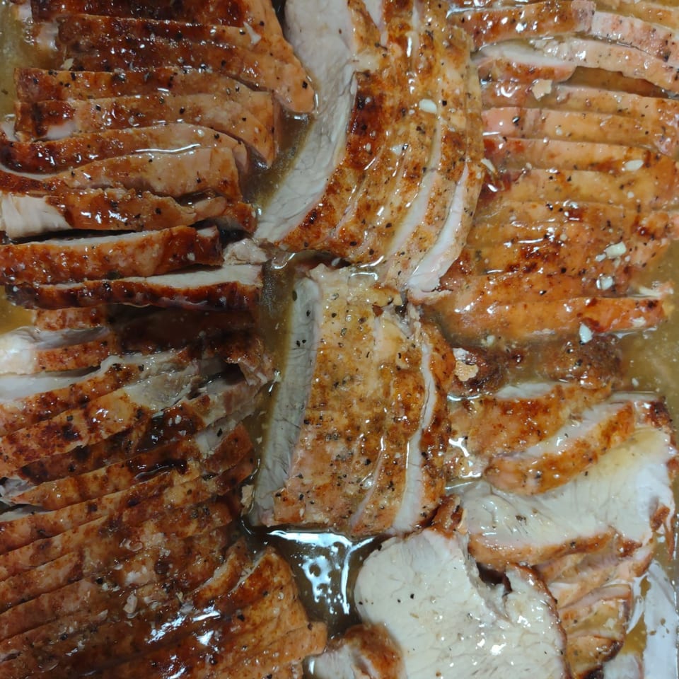 Close-up of sliced, seasoned Southern-style turkey or chicken breast in a savory sauce.