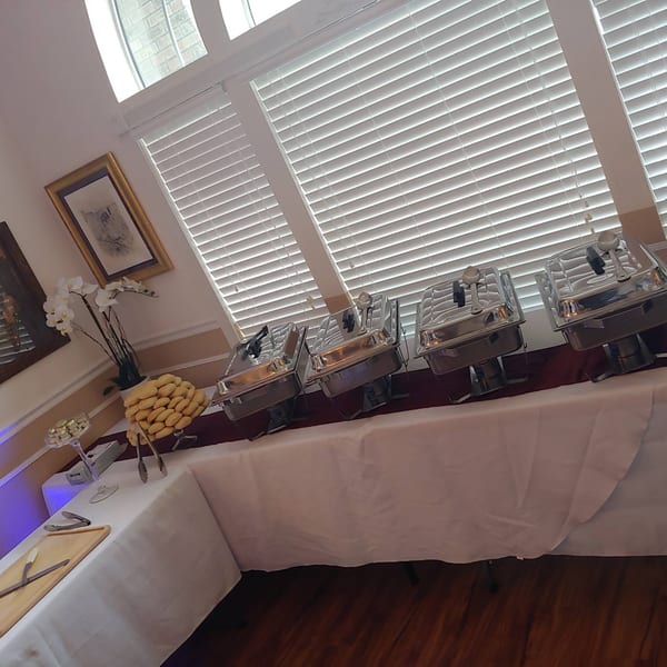 A buffet table with chafing dishes, a platter of biscuits, and white orchids at Southern Taste Cafe.