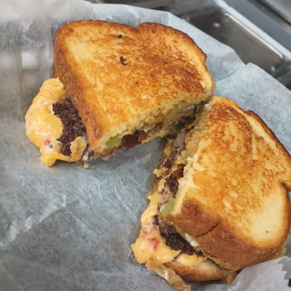 A Southern Taste Cafe patty melt, cut in half, with melted cheese, onions, and pickles.