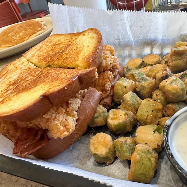 Southern Taste Cafe's fried chicken and bacon sandwich with a side of fried okra and dipping sauce.